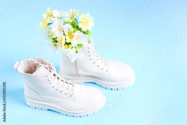 Fototapeta White demi-season martens boots with a bouquet of spring flowers on a light blue.