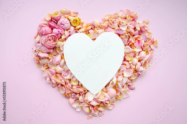 Fototapeta Heart made of pink and yellow rose petals. White paper heart over roses. Top view with copy space for your text. Love and romantic concept. Valentine's, Mother's Day, Women's Day, wedding.