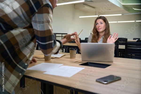 Fototapeta Young woman arguing with her male colleague in the office