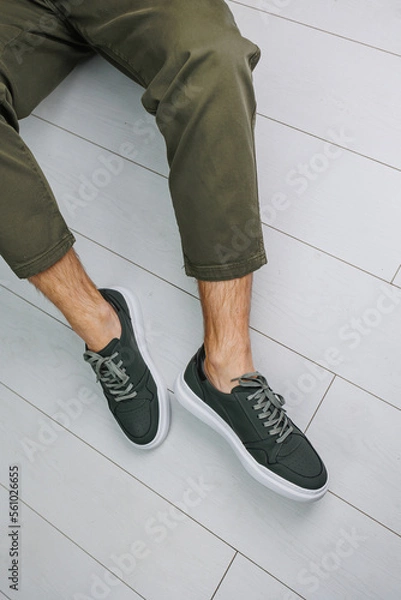 Fototapeta Male legs in pants and green casual sneakers. Men's fashionable shoes