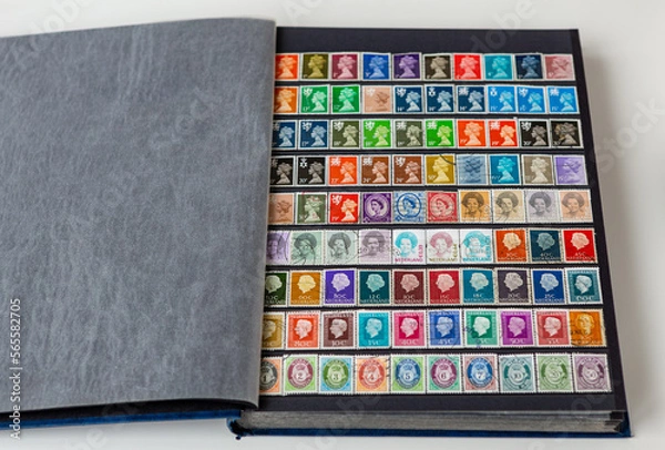 Fototapeta Collection vintage postage stamp set in open album. Collectible book with English and Nederland postage stamps showing Portrait of Queen Elizabeth 2nd, Beatrix and Juliana.