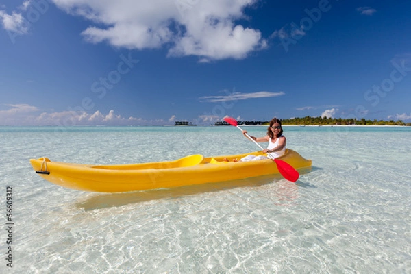 Fototapeta Young caucasian woman kayaking in sea at Maldives