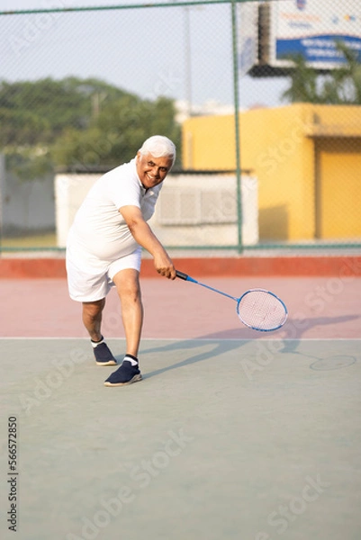 Obraz Senior man playing badminton outdoor at badminton court. Concept of active lifestyle being on pension