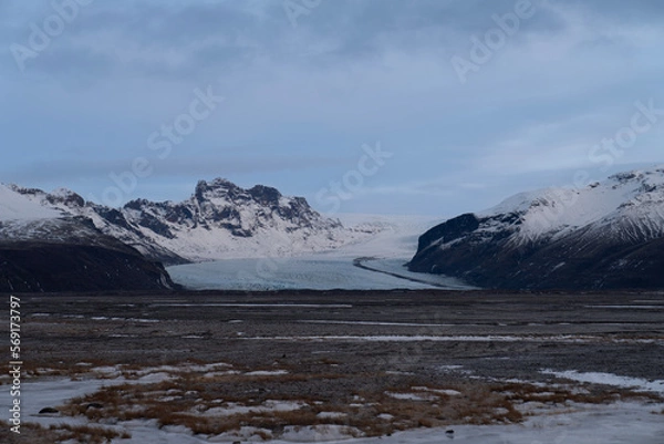 Fototapeta Glaciers cascade down snow-capped mountain canyons and plains carved by volcanic activity.