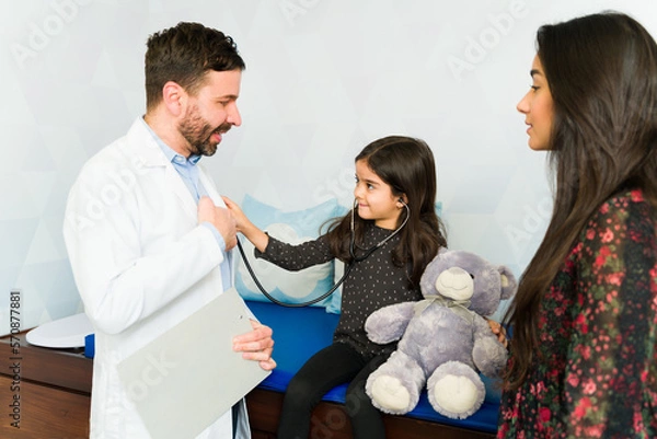 Fototapeta Funny pediatrician playing with a kid patient