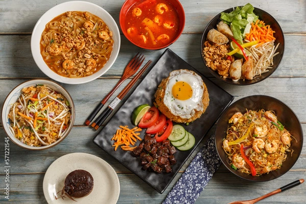 Fototapeta Composition des plats asiatique dans une vaisselle colorée, servie sur fond rustique bleu, vue de dessus. Ensemble de cuisine chinoise, vietnamienne, thaïlandaise. 