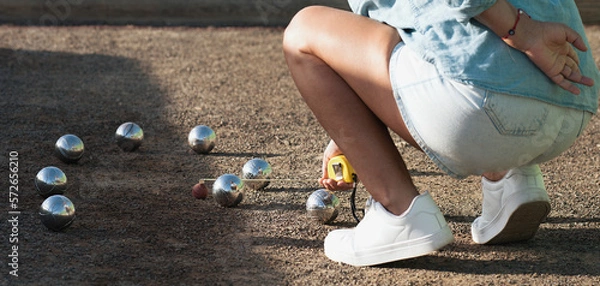 Fototapeta Petanque game, woman measuring the distance of petanque ball in petanque field, deciding who's the winner