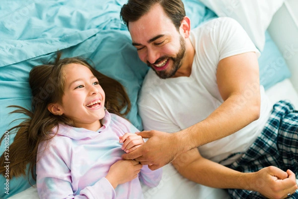 Fototapeta Cheerful dad laughing and playing with her daughter