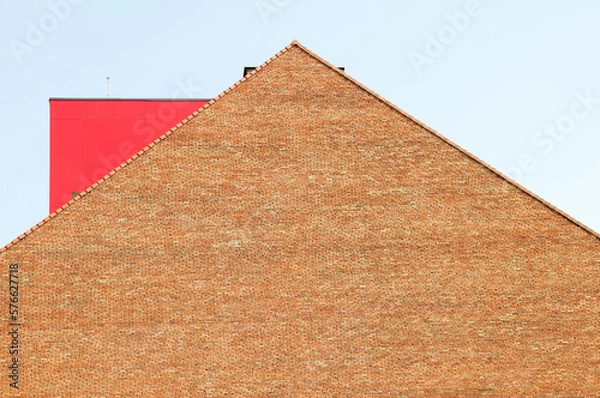 Obraz Red brick building top with a red metal object on the roof.