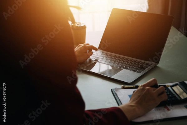 Fototapeta Attractive smiling young asian business woman work at home office, Asian woman working on laptop computer holding tablet.