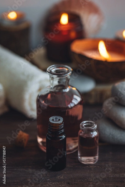 Fototapeta Concept of natural essential organic oils, Bali spa, beauty treatment, relax time. Atmosphere of relaxation, pleasure. Candles, towels, dark wooden background. Alternative oriental medicine