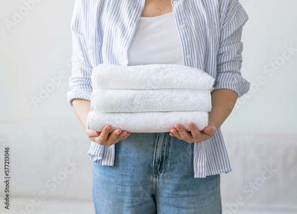 Fototapeta Woman holds stack clean white towels in her hands. Concept of cleaning washing and cleanliness