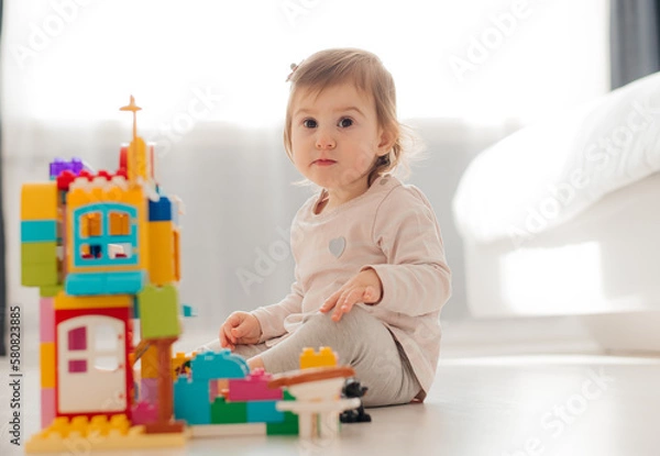 Fototapeta adorable child playing with multicolored building blocks on floor