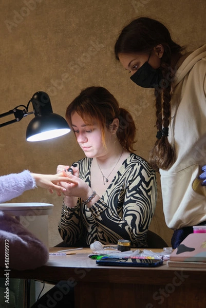 Fototapeta A young woman mentor teacher coach conducts individual training in manicure techniques.