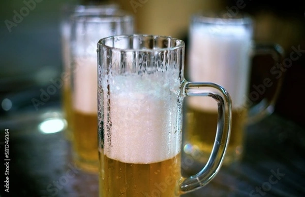 Fototapeta detail of a mug of pils beer with white foam on a brewery table waiting to be filled by the brewmaster