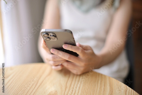 Fototapeta Woman hand using a smartphone for Stock exchange trading online in the coffee shop, business concept