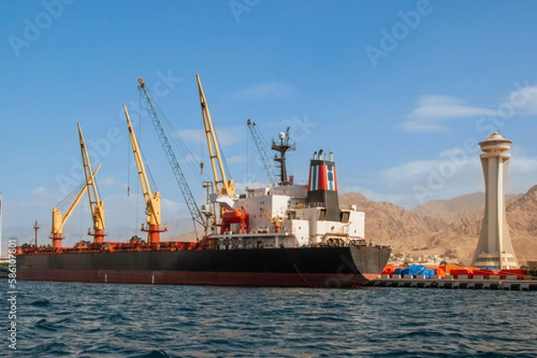 Fototapeta Jordan. Aqaba. Container ship moored at the dock for loading. There are several cranes on pier. Aqaba, Jordan, December 6, 2009