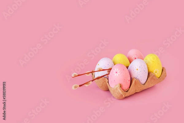 Fototapeta Eco basket with colorful easter eggs and willow branch on pastel light pink background. minimalistic decoration, minimal composition. Front view, place for text, banner