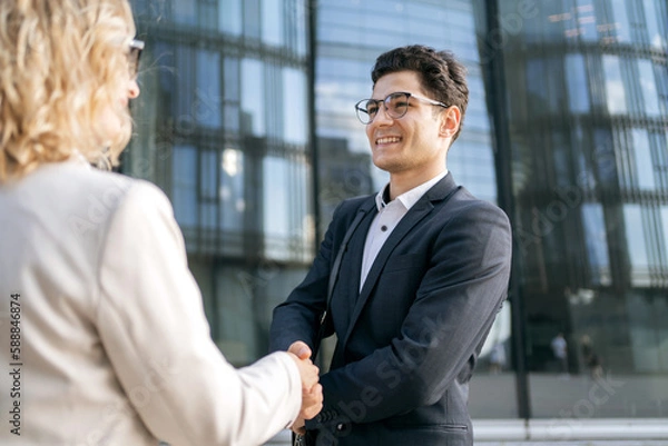 Fototapeta Meeting two colleagues, a woman and a man, persons in business suits going to work in a new office.