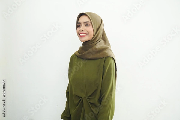 Fototapeta Smiling young Asian Muslim woman feels confident and joyful isolated over white background. Ramadan Concept.