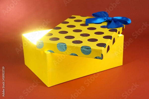 Fototapeta Gift box with bright light on it on red background