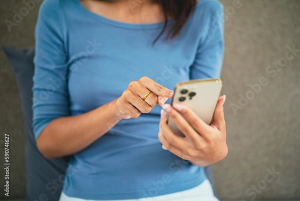 Fototapeta Asian Woman with Smartphone on sofa working mobile devices. cell telephone technology e-commerce concept. Relax at home