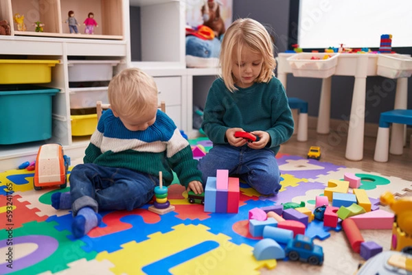 Obraz Adorable boy and girl playing with construction blocks sitting on floor at kindergarten