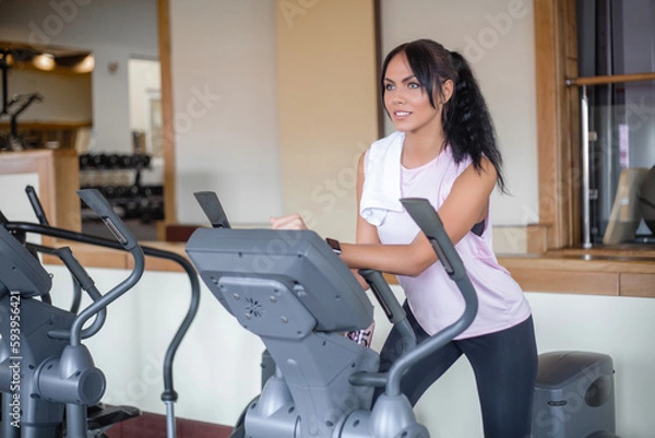 Fototapeta Attractive young sports woman is working out in gym.