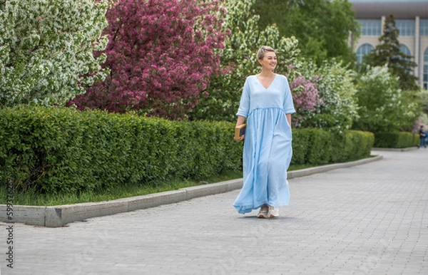 Fototapeta Portrait of a young beautiful blonde woman in blue dress