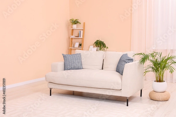 Fototapeta Comfortable sofa and potted plants at home. Interior design