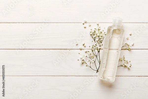 Fototapeta Fancy healthcare bottles for serum, micellar, tonic, toner, lotion, water and cream with gypsophila branch. Natural oranic spa cosmetics concept. Mockup, template, Top view