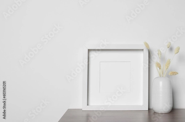 Obraz Empty photo frame and vase with dry decorative spikes on wooden table. Mockup for design