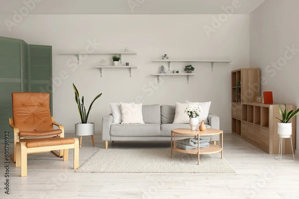 Fototapeta Interior of living room with grey sofa, brown armchair and wooden coffee table