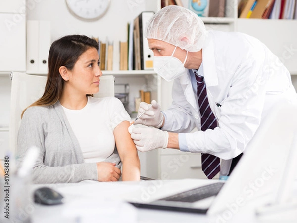 Fototapeta Doctor giving Covid-19 or flu antivirus vaccine shot to patient wear face mask protection at medical office