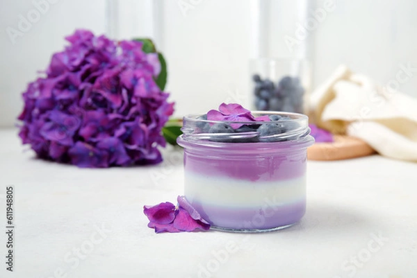 Fototapeta Glass jar of panna cotta with blueberry and beautiful hydrangea flowers on white table