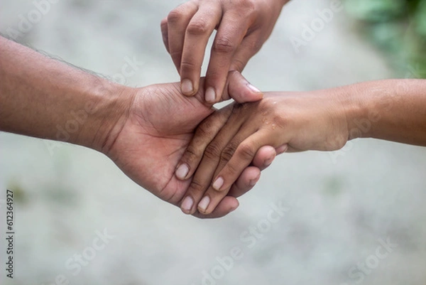 Fototapeta Tow friends are hand shaking, one with white hands and the other with black hands.