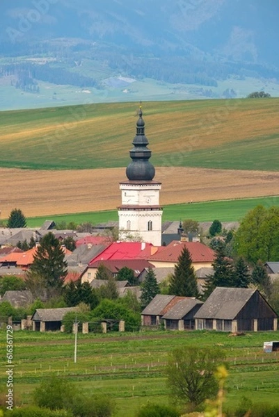 Fototapeta Old village with a tower, gardens and cultivated fields below the hills. Partizanska Lupca, near Liptovsky Mikulas, Liptov region, Slovakia