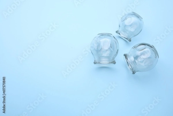 Fototapeta Glass cups on light blue background, flat lay with space for text. Cupping therapy