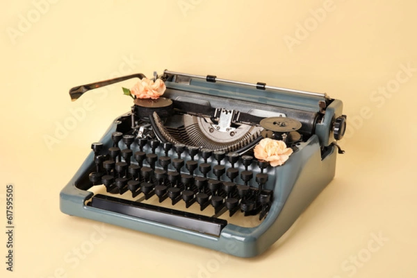 Fototapeta Vintage typewriter with carnation flowers on yellow background