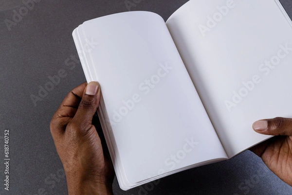 Fototapeta Hands of biracial man holding book with copy space on grey background