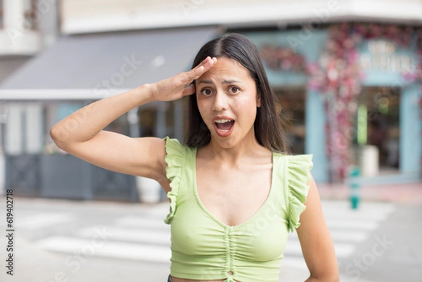 Fototapeta pretty hispanic woman looking happy, astonished and surprised, smiling and realizing amazing and incredible good news