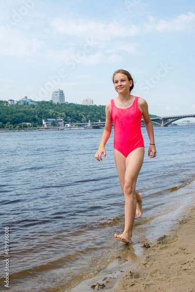 Fototapeta A girl runs along the river in the summer.