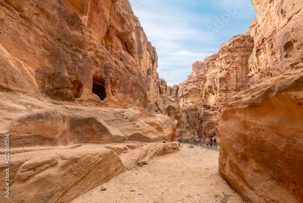 Obraz Visitors pass through the canyon ravine on the way to the Treasury building in the ancient Nabataean Rose City of Petra, Jordan.