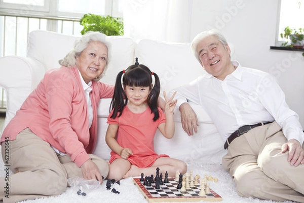 Fototapeta .Senior couple with granddaughter playing game of go.