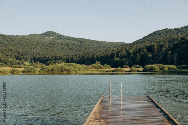 Fototapeta wooden pier lake surrounded by mountains, Slovenia. The concept of summer holidays, holidays