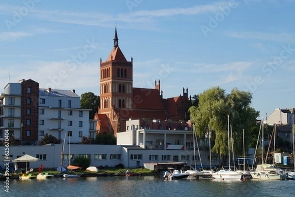 Fototapeta View from the lake to the city and the Church of St. Nicholas in Chelmza.