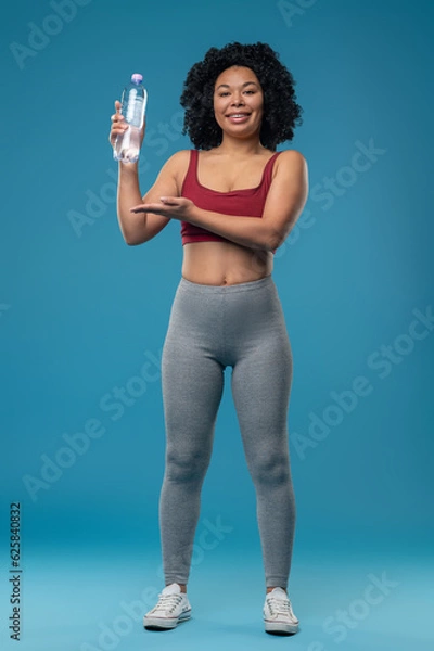 Fototapeta Sporty woman in sportswear with a bottle of water