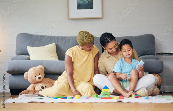 Fototapeta Playing, gay family and child with toys on a home floor for development, education and learning. Adoption, lesbian or LGBT women or parents and kid together in a lounge for quality time and fun