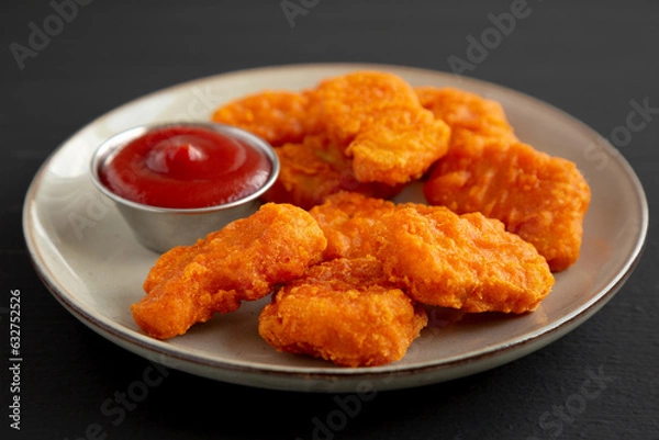 Obraz Homemade Spicy Chicken Nuggets on a Plate on a black background, side view.