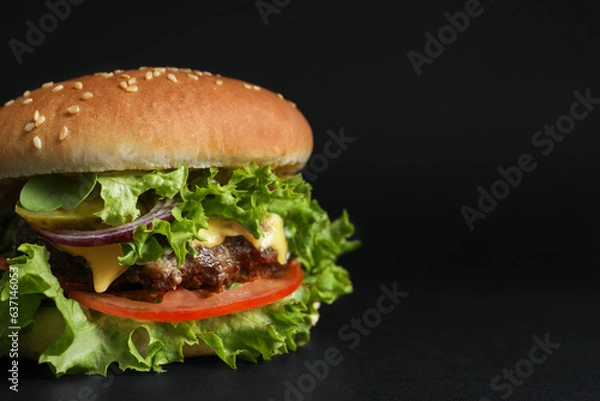 Fototapeta Delicious burger with beef patty and lettuce on black background, closeup. Space for text